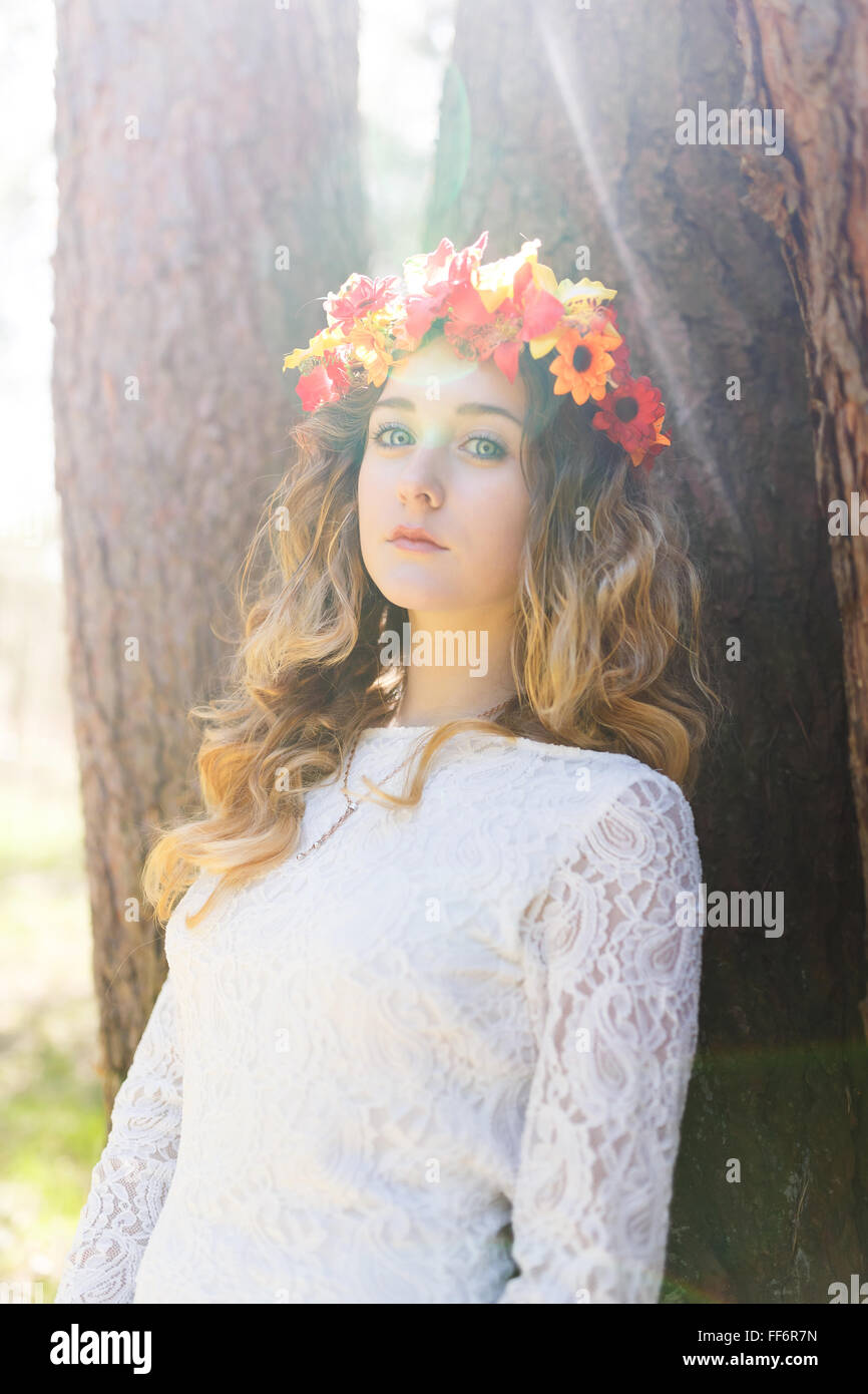 Portrait of a beautiful girl with flowers in her hair near tree at ...