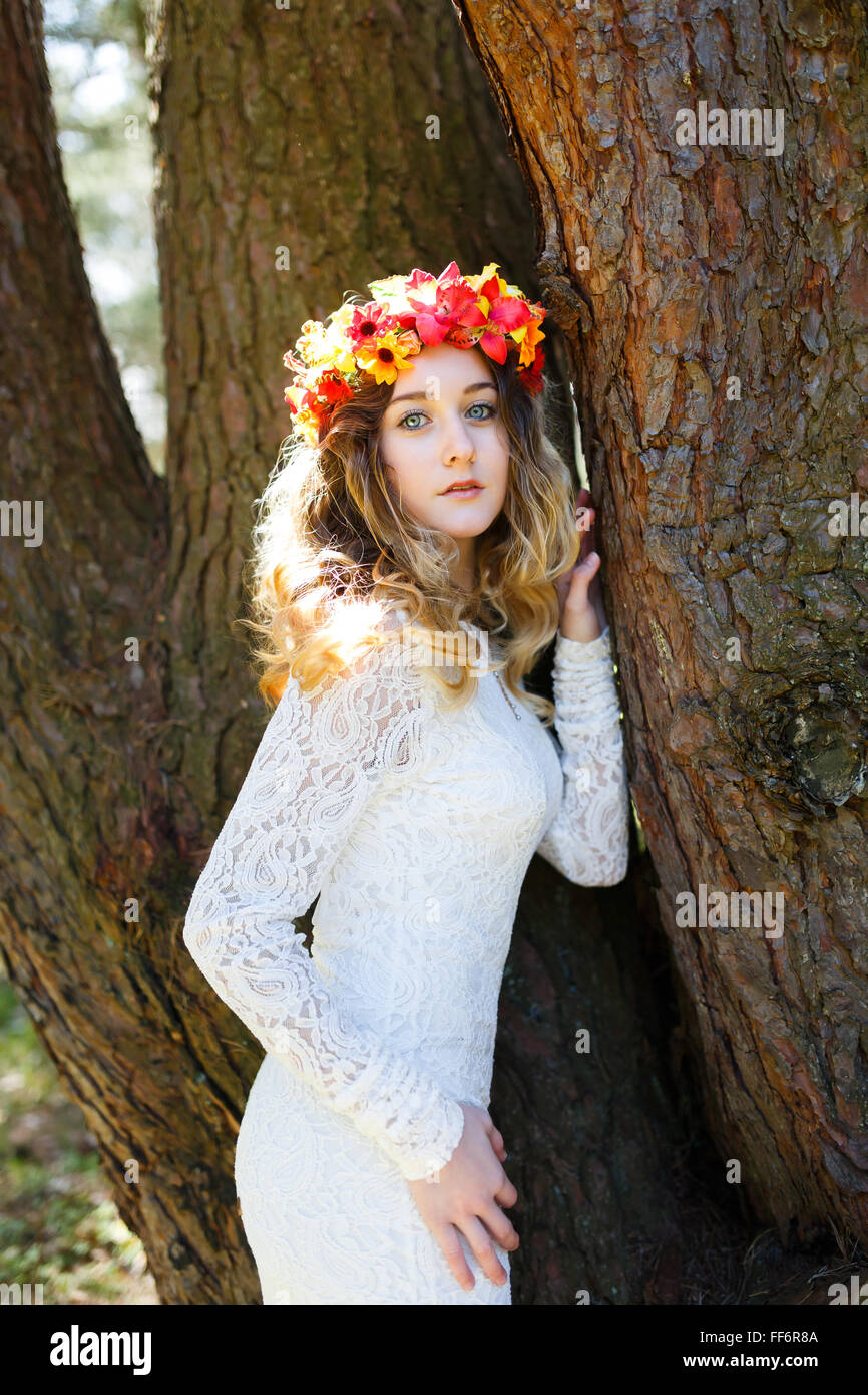 Portrait of a beautiful girl with flowers in her hair near tree at spring time Stock Photo