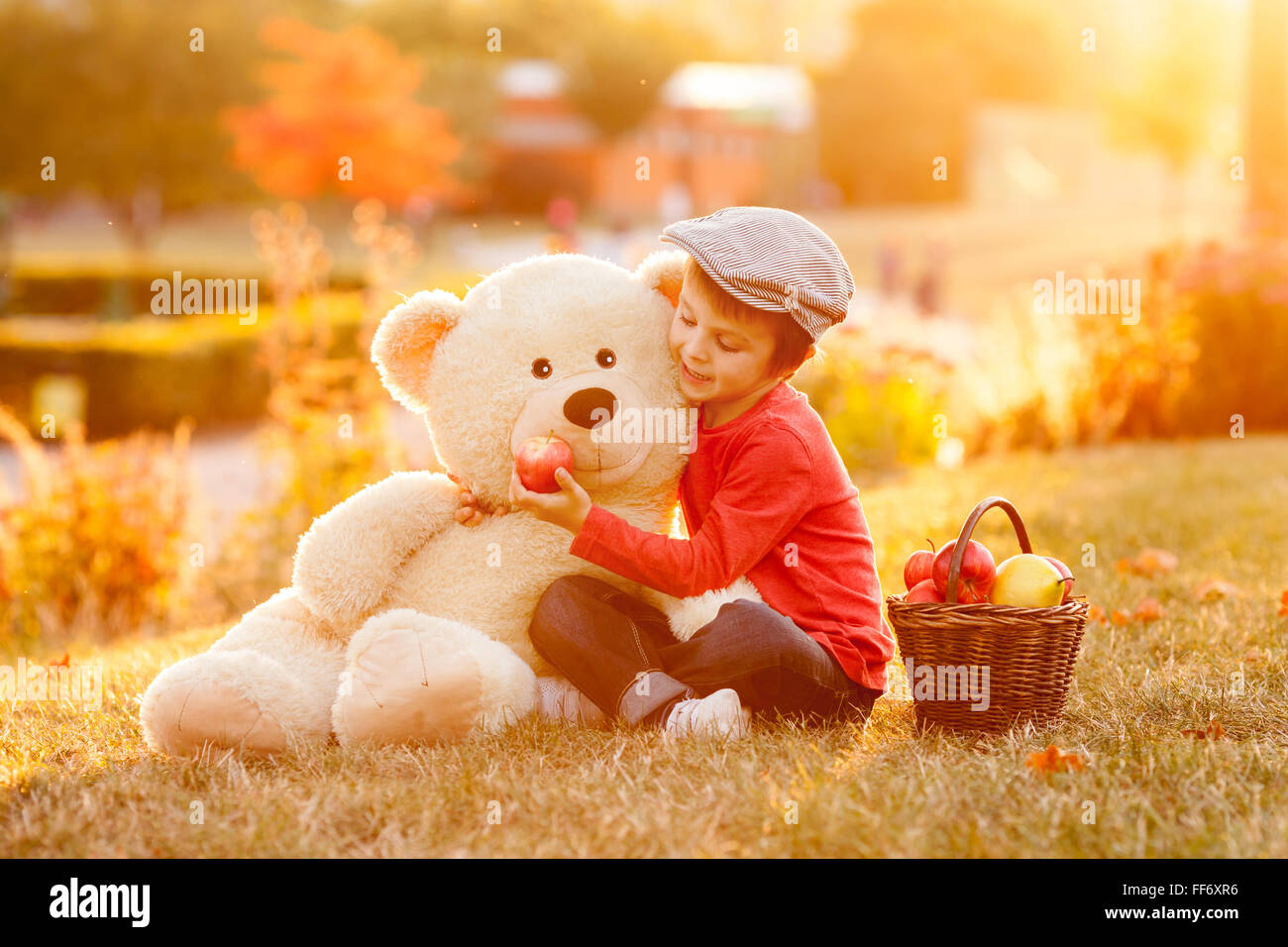 Adorable little boy with his teddy bear friend in the park on sunset ...