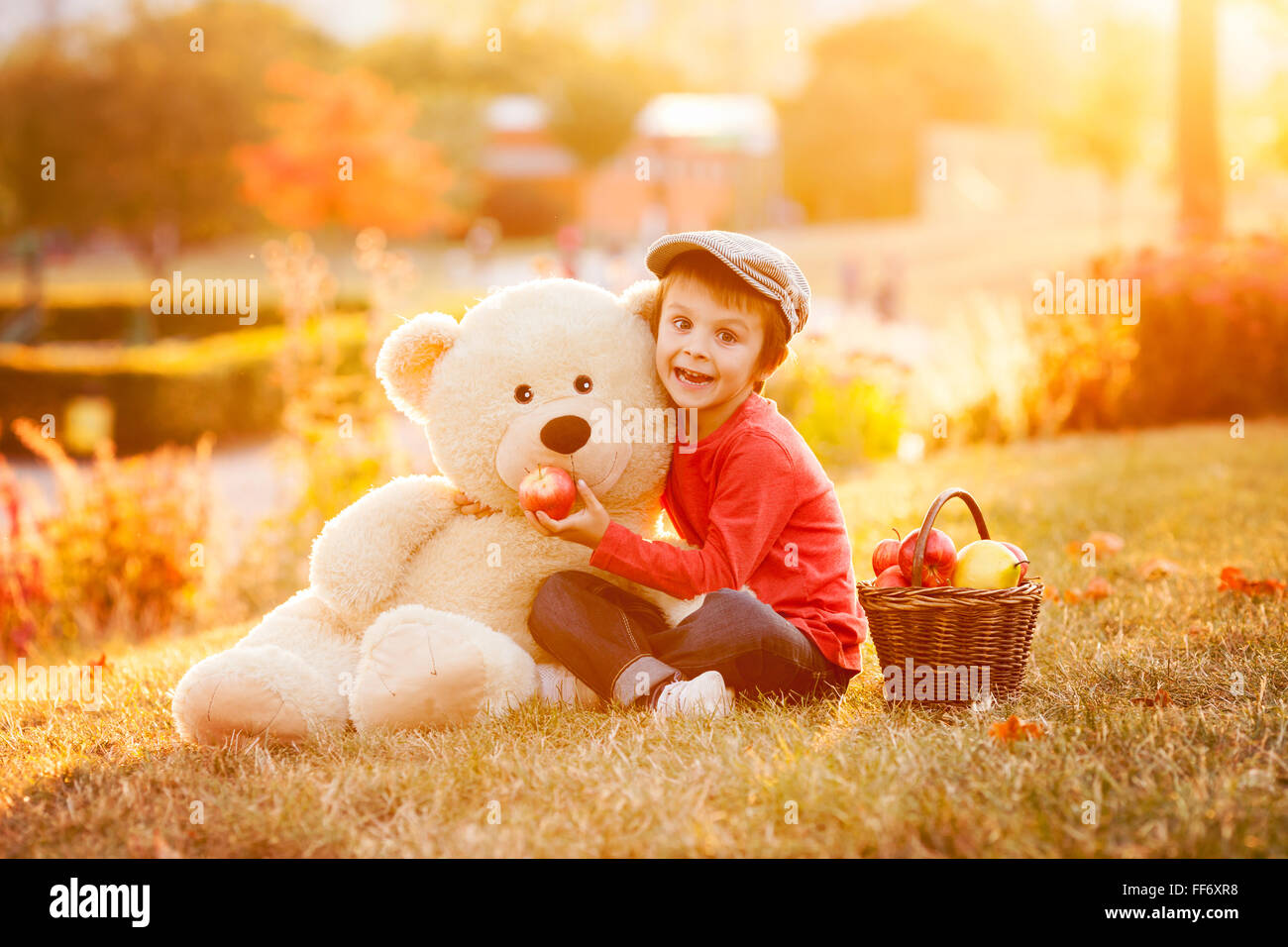 Adorable little boy with his teddy bear friend in the park on sunset ...