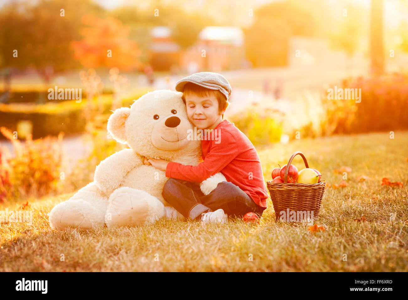 Adorable little boy with his teddy bear friend in the park on sunset ...