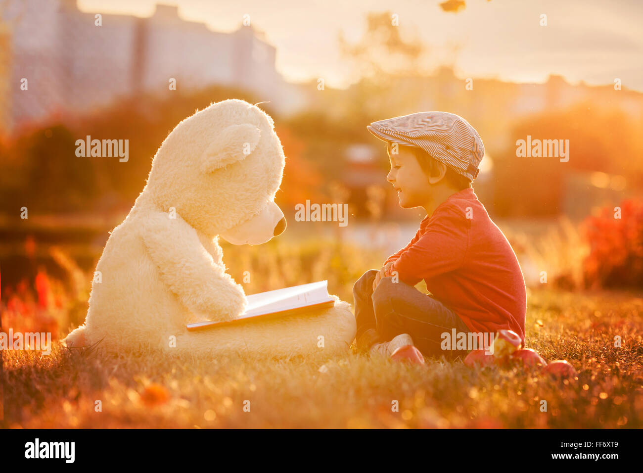 Adorable little boy with his teddy bear friend in the park on sunset ...