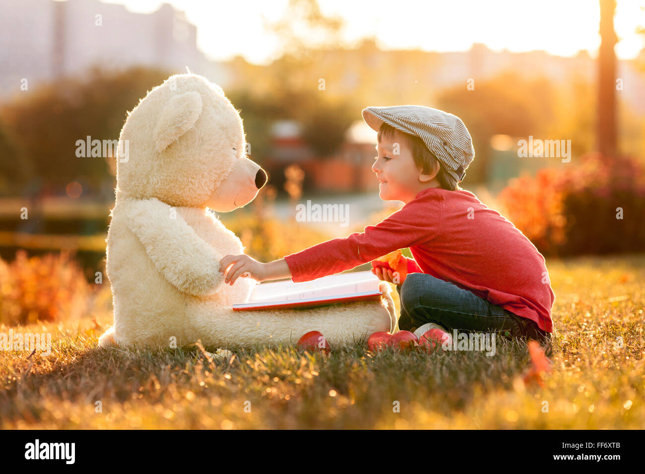Adorable little boy with his teddy bear friend in the park on sunset ...
