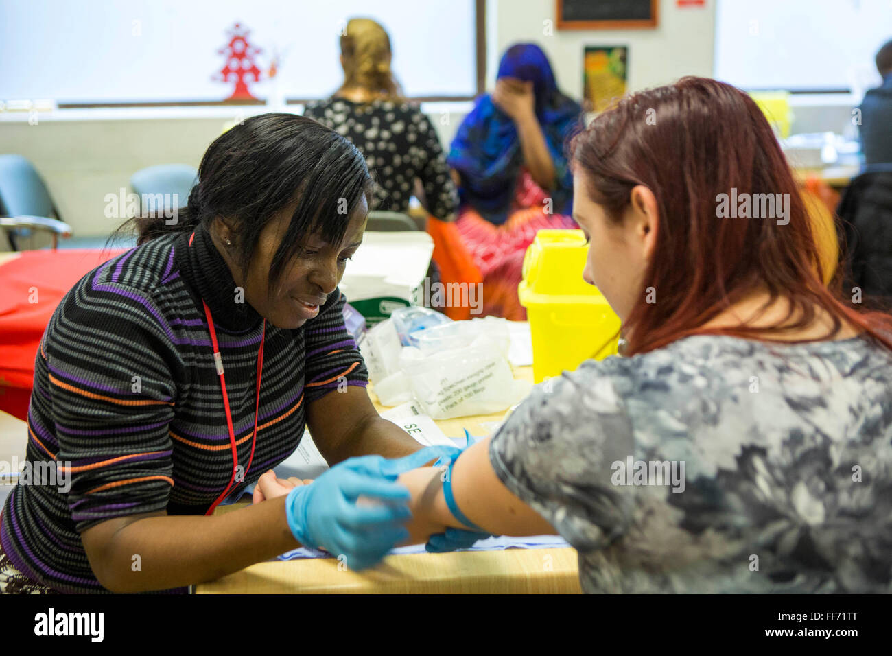 A tuberculosis contact tracing nurse prepares a young females arm for a blood test.  This is part of public health screening event in response from some recent TB cases being diagnosed in a homeless hostel in central London, UK. Stock Photo