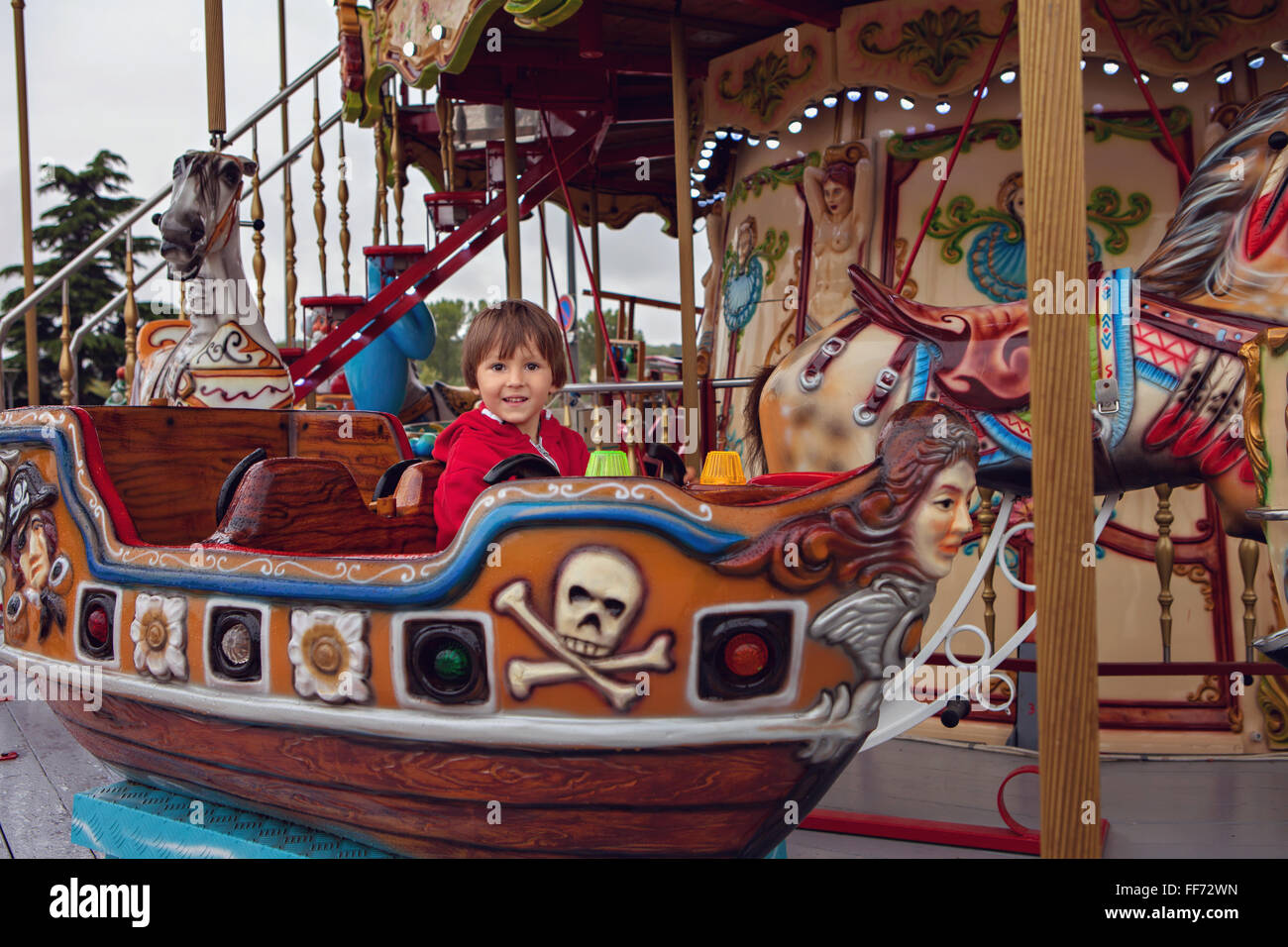 Sweet boy, riding in a train on a merry-go-round, carousel attraction ...