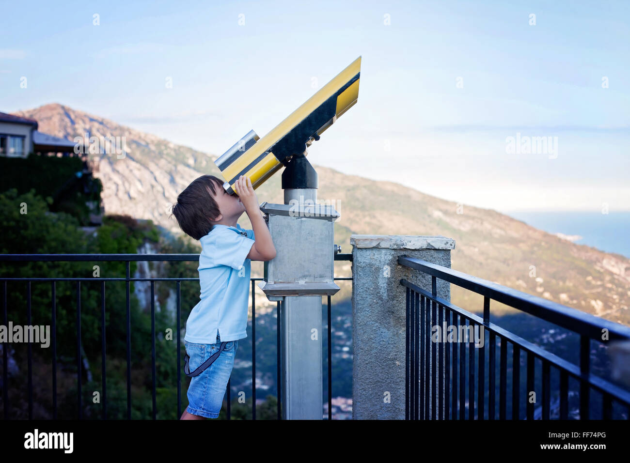 Curious boy, looking through a telescope at something interesting, summertime Stock Photo