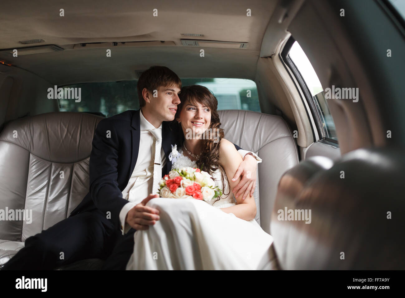 Happy bride and groom embracing sitting in the car Stock Photo