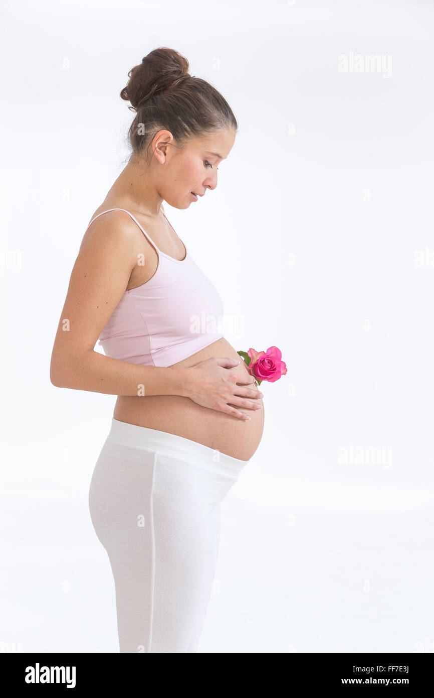 pregnant asian woman with a rose in hands on her belly, isolated against white background Stock Photo