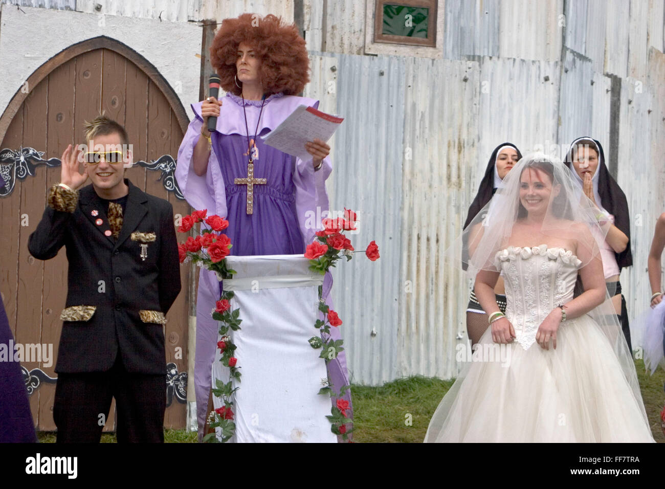A couple get married outside the Chapel of love and loathing in the Lost Vagueness area at the Glastonbury festival. Stock Photo