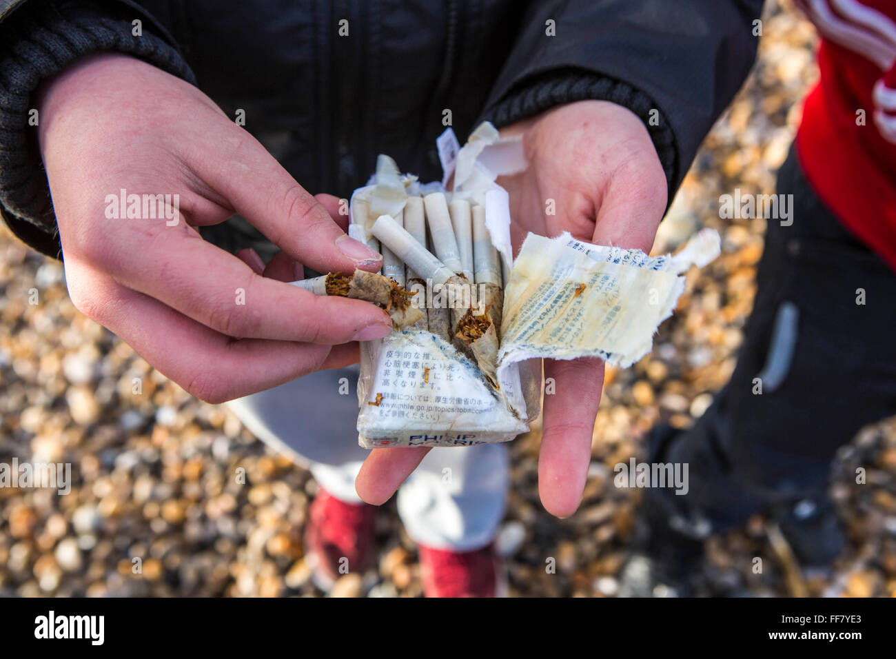 A person holds a packet of wet cigarettes in their hand. The cigarette