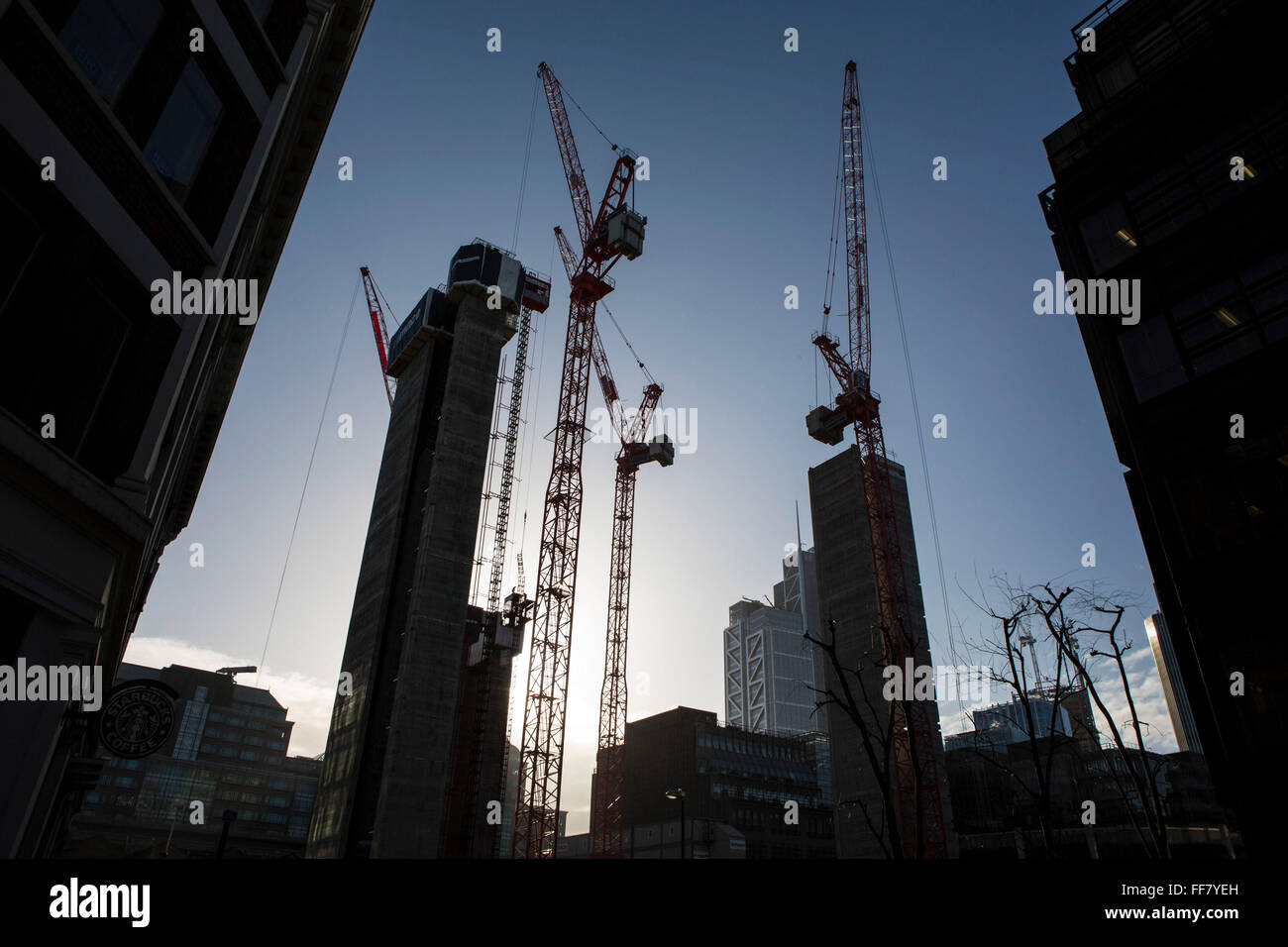 Red construction cranes are silhouetted by the sun on a Mace construction site, Broadgate, next