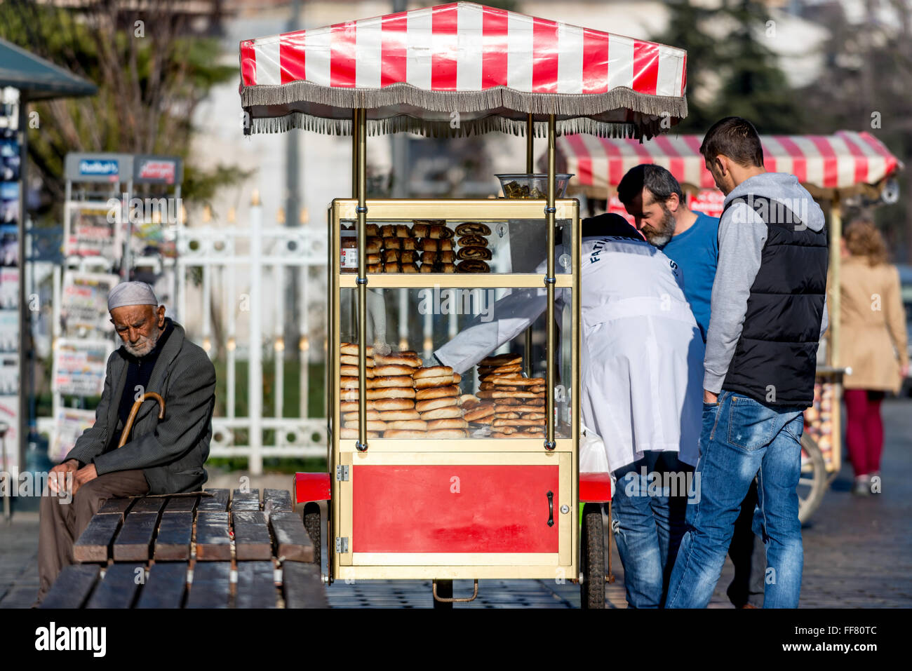 An old man sits next to a pretzel stall near the Sultan Ahmed Mosque in Istanbul, Turkey. Stock Photo
