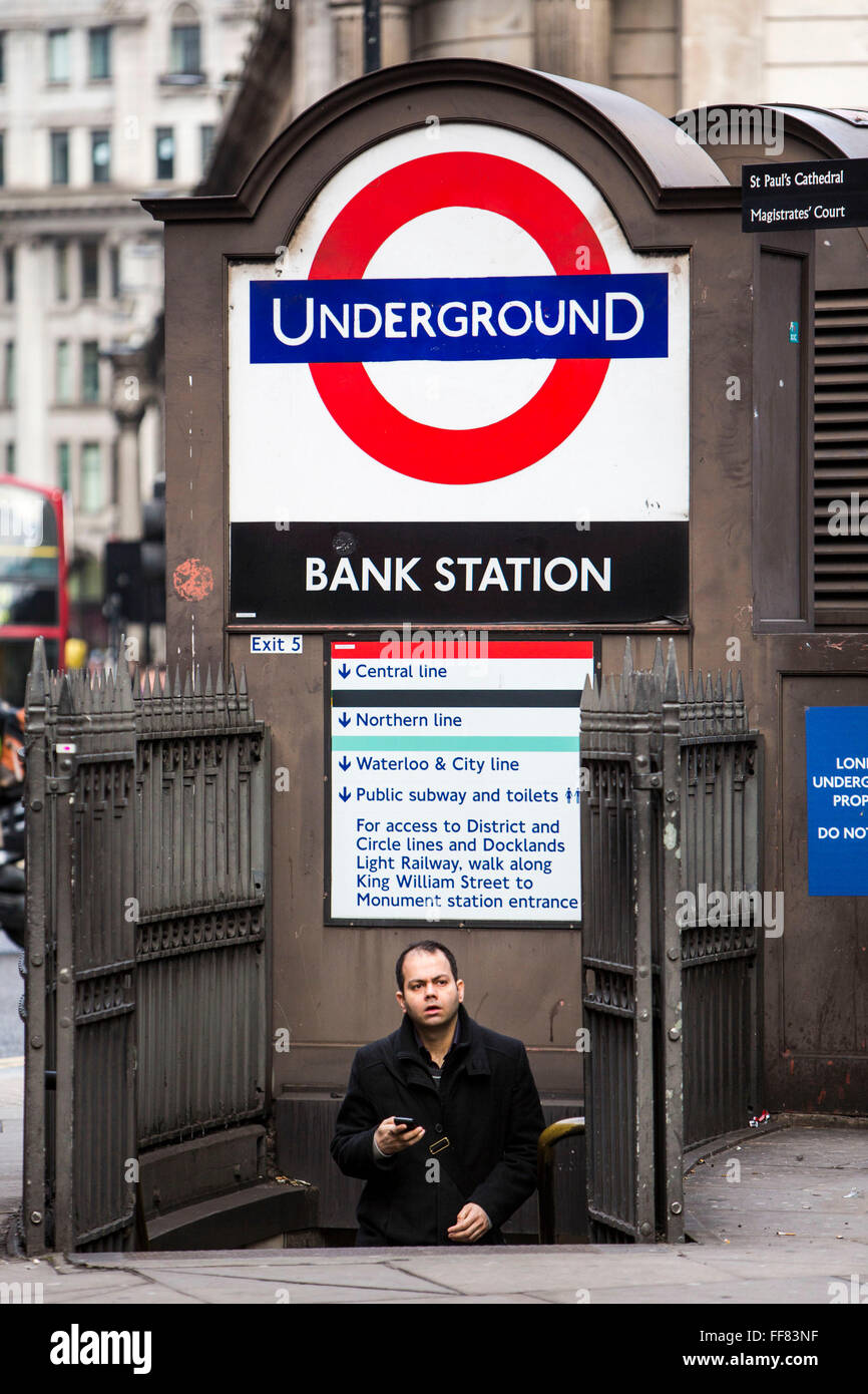 A British male walks up the steps of the subway to leave London Underground Bank Station, holding his mobile phone, United Kingdom.  Bank station opened in 1900 and is named after the Bank of England.  It is served by the Central, Northern and Waterloo and City lines.  Due to is central City of London location, the station complex is the ninth-busiest on the London Underground network. Stock Photo