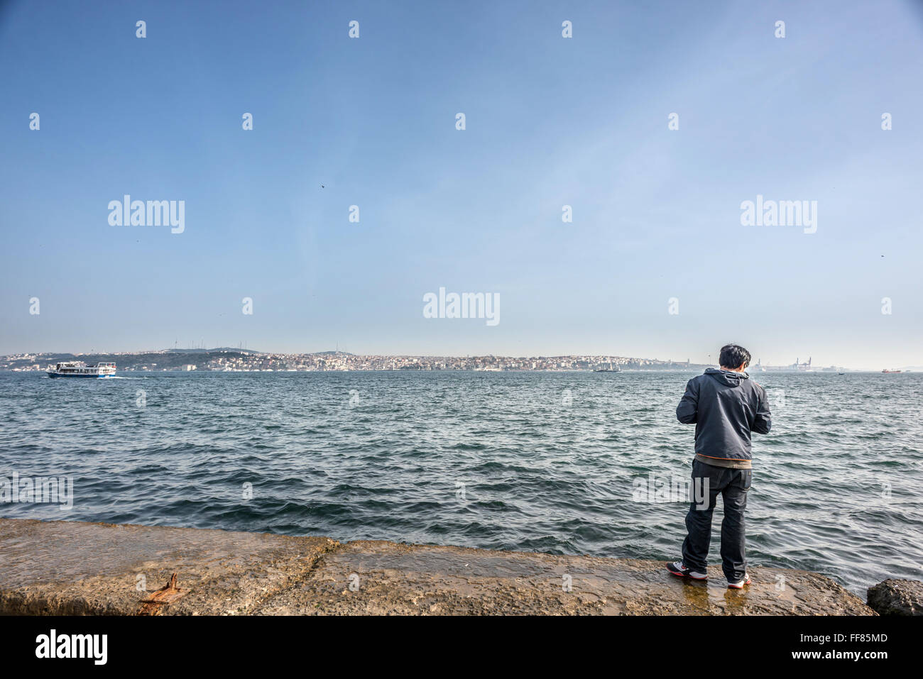 A young man looks out over the River Bosphorus from one side of Istanbul to the other. Stock Photo