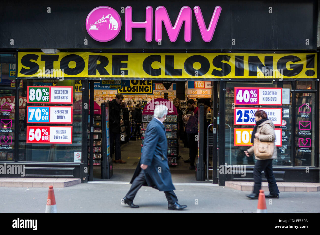 A British city worker walks past an HMV entertainment retail store in the Square Mile, central London, United Kingdom.  The shop is having a closing down sale and due to the economic downturn the British retailing company entered administration in January 2013. Stock Photo
