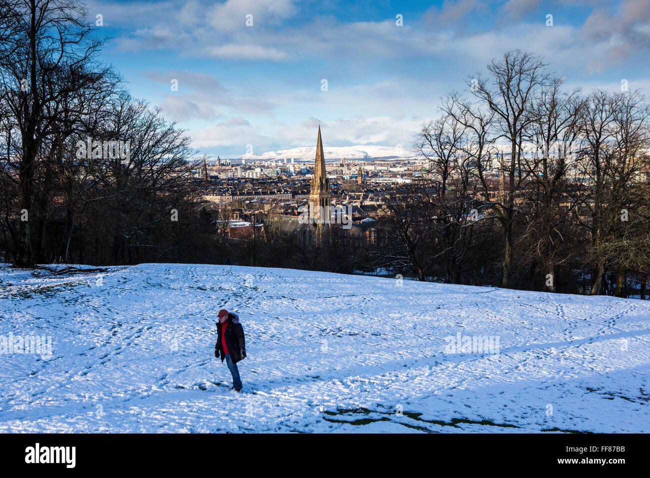 A man walks in the snow, Queens Park, Glasgow.  The park is known for its view across the south side of Glasgow, with a snow covered Campsie Fells in the background. Stock Photo
