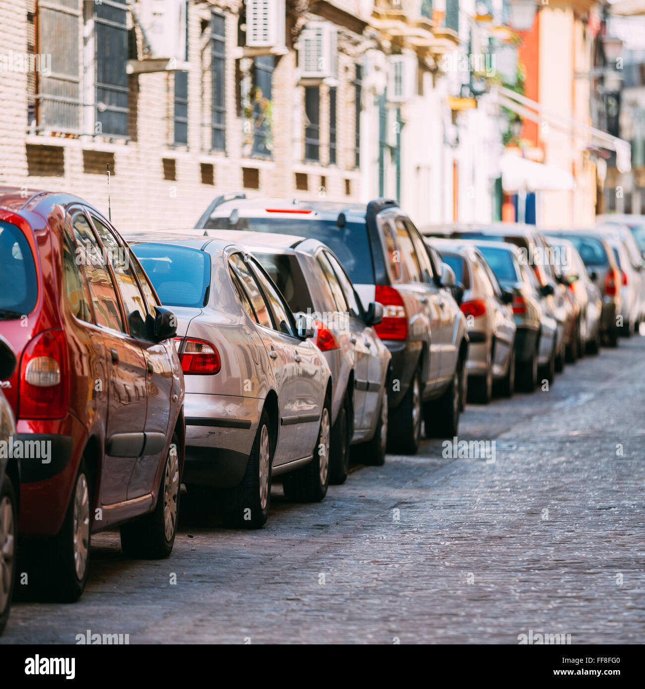 Cars parked on street in European city in sunny summer day. Stock Photo