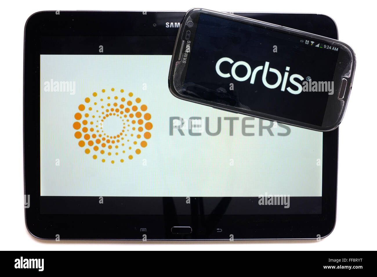 The news agencies Corbis and Reuters on the screens of a tablet and a smartphone photographed against a white background. Stock Photo