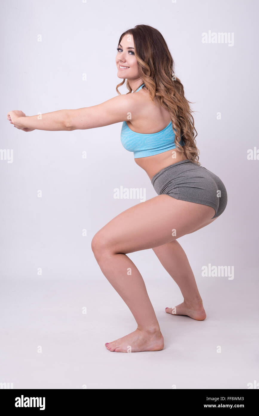 model doing squats in gym wear, fitness clothes toning backside Stock Photo