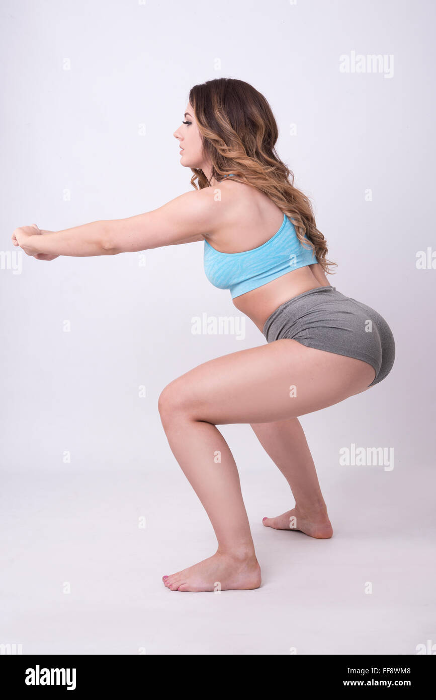 model doing squats in gym wear, fitness clothes toning backside Stock Photo