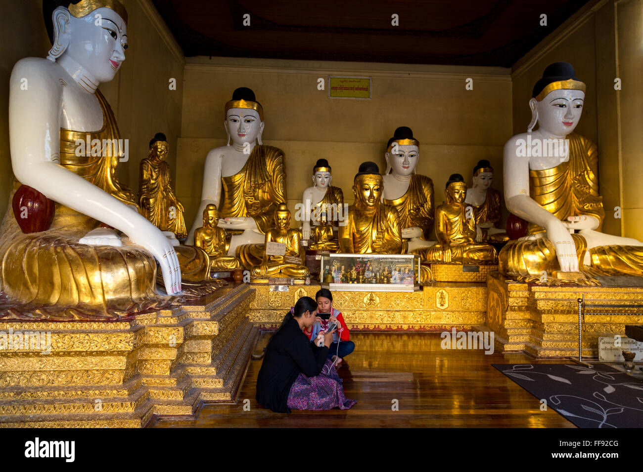 Yangon, Myanmar, 9th November 2015: The Shwedagon pagoda in Yangon embraces people, not just to worship, here two young girls ar Stock Photo