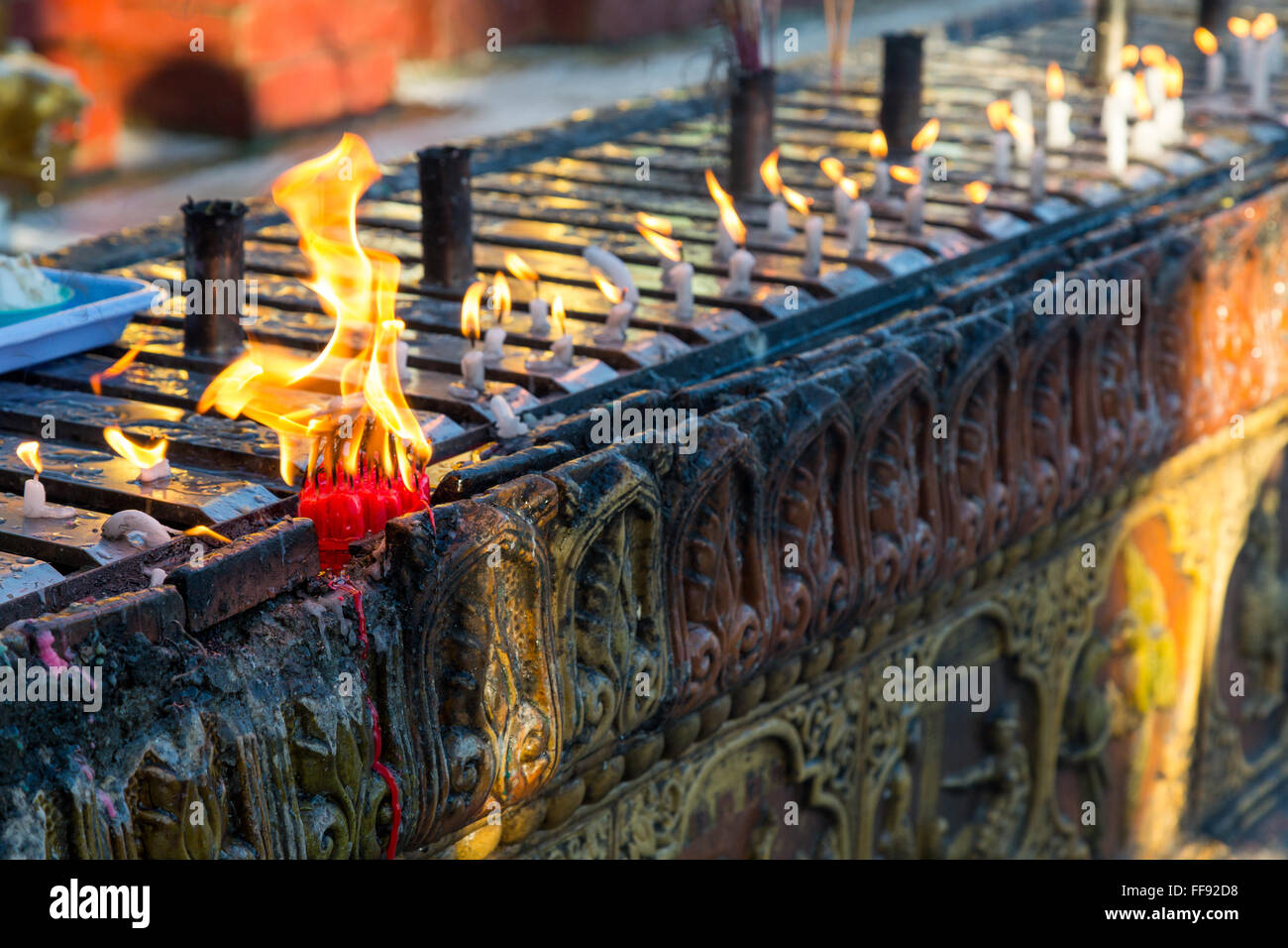 A cluster of candles burning on an carved wall at the Shwedagon pagoda in Yangon Stock Photo