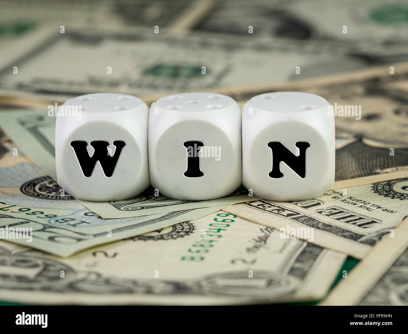 Three white dice placed on pile of money spelling WIN word Stock Photo