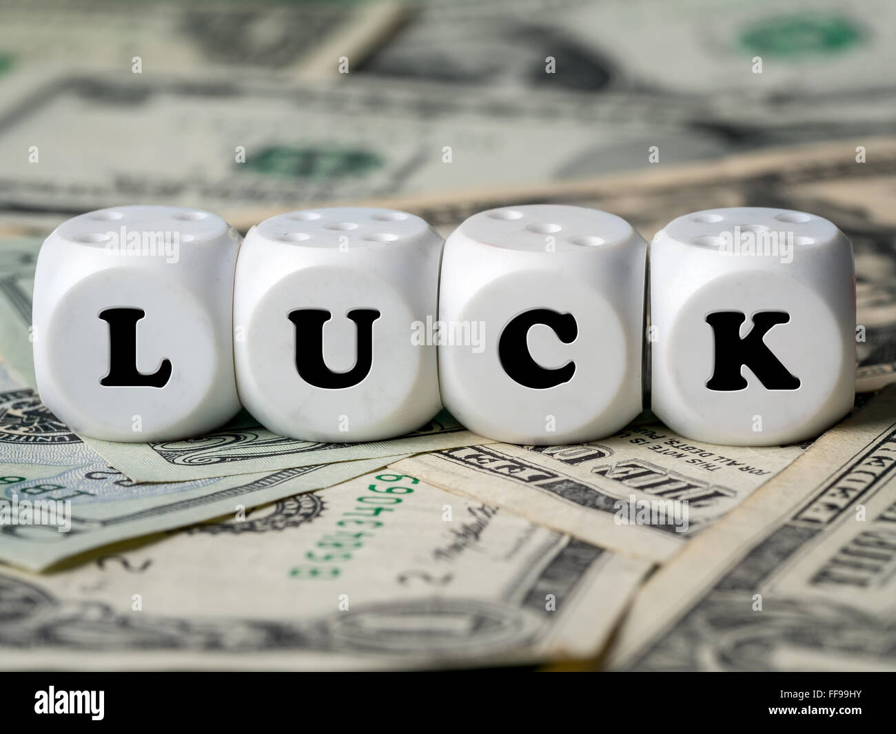 Three white dice placed on pile of money spelling LUCK word Stock Photo