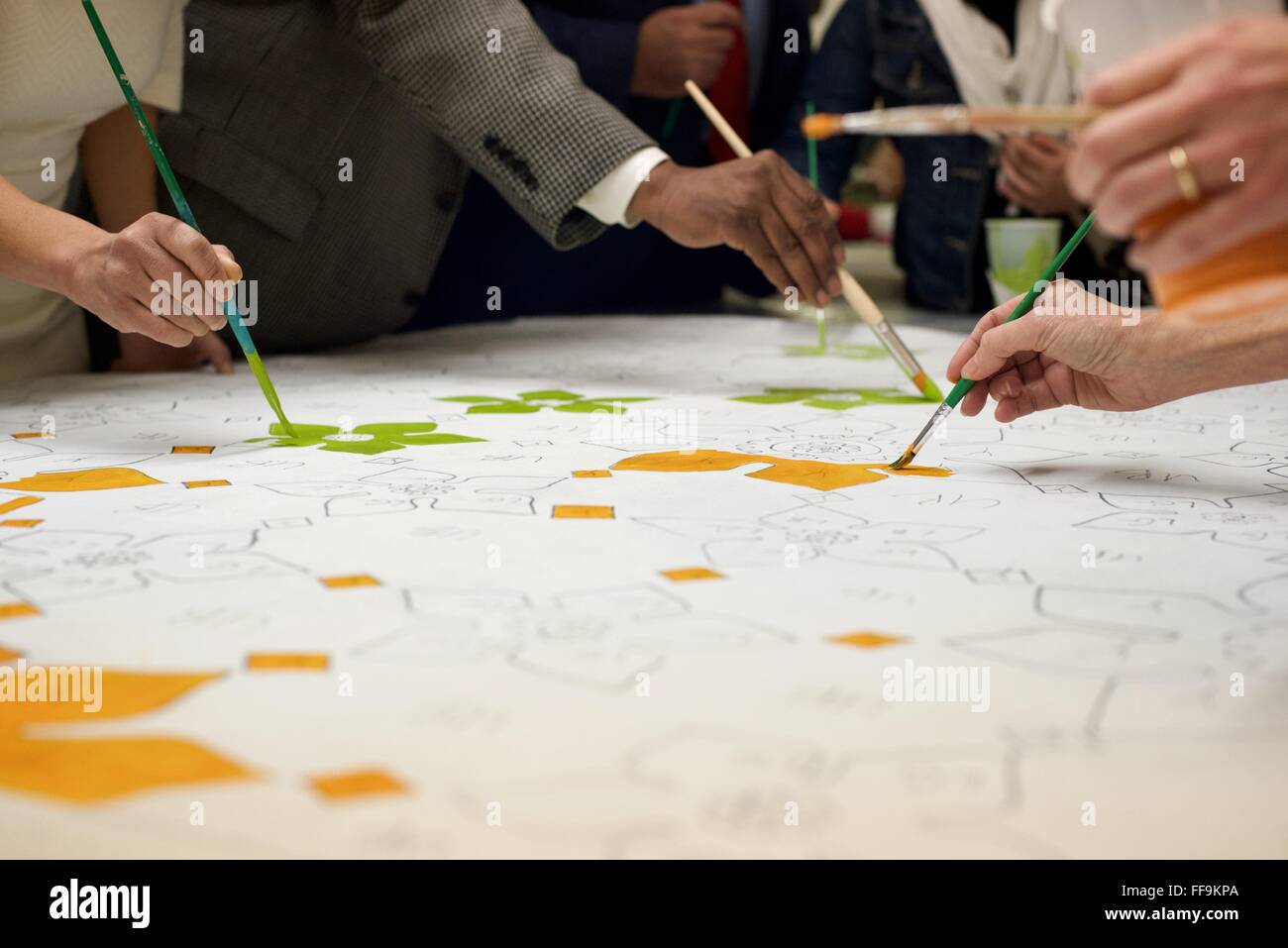 Community members help fill in the decorative elements of what will become parts of a mural outside a North-Philadelphia mosque. Stock Photo