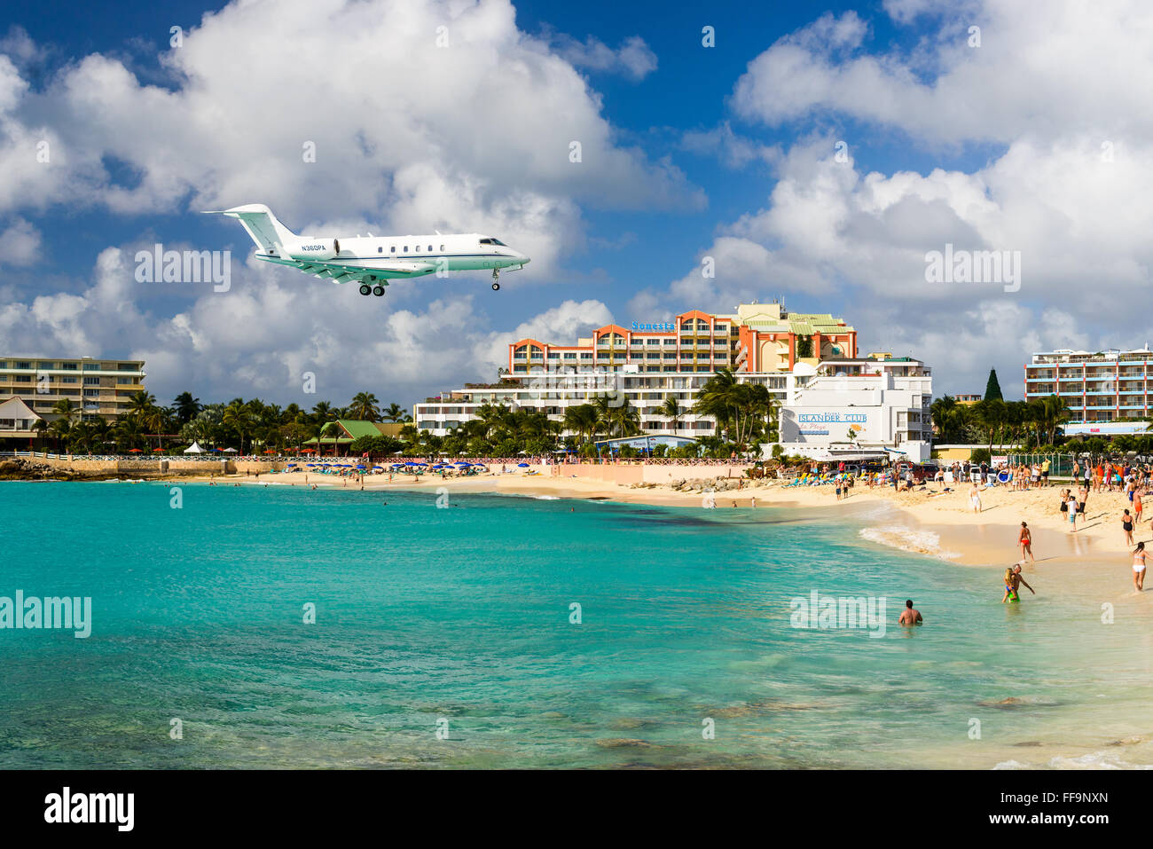 A jet approaches Princess Juliana Airport above onlookers on Maho Beach in Philipsburg, Sint Maarten. Stock Photo