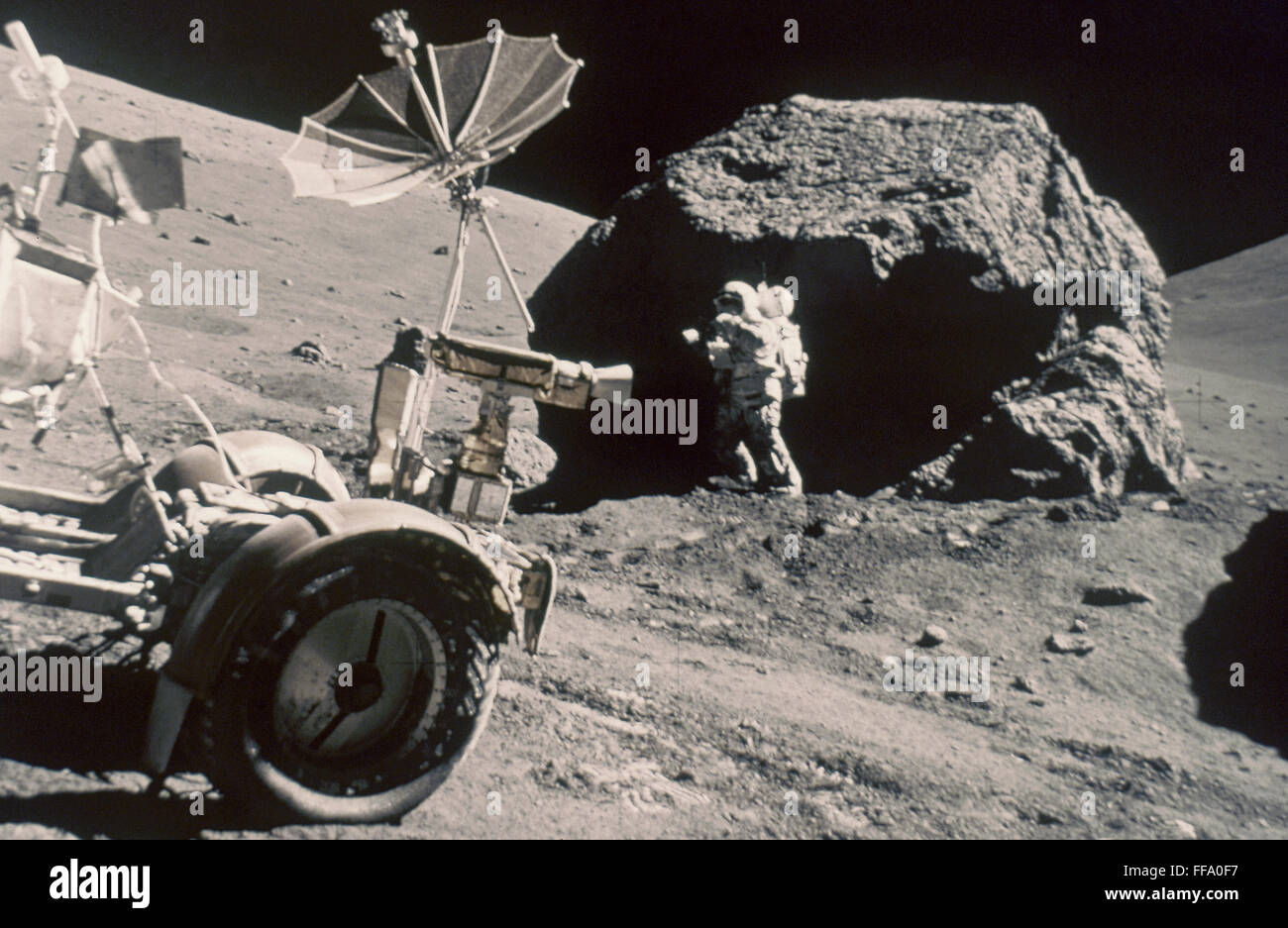APOLLO 17, DECEMBER 1972: /nFront of Lunar Rover and Schmitt working by large boulder. Stock Photo