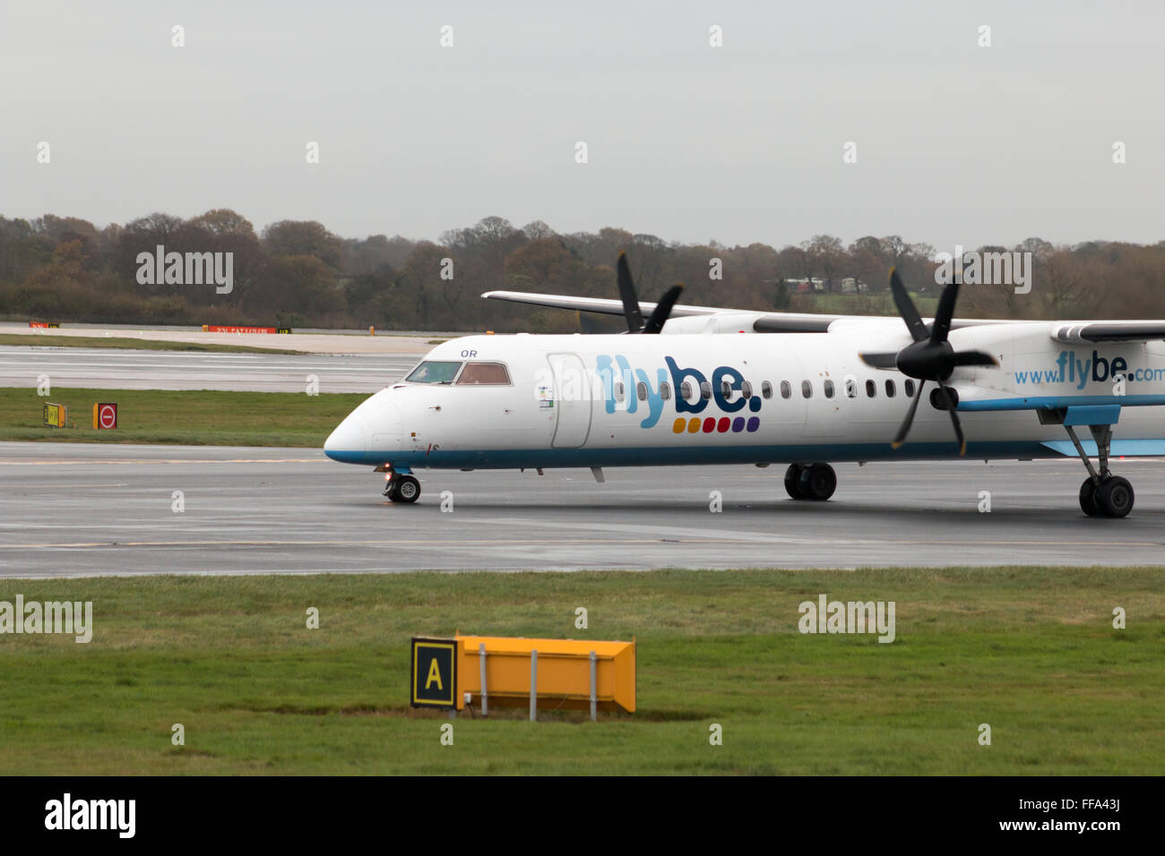 Flybe Bombardier Dash 8 Q400 regional turboprop passenger plane (G-ECOR) taxiing on Manchester International Airport runway. Stock Photo