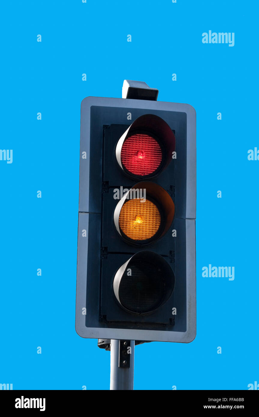 Red and amber traffic lights against blue sky background. Stock Photo
