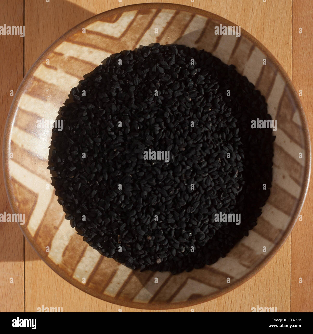 Nigella seeds in patterned wooden bowl Stock Photo