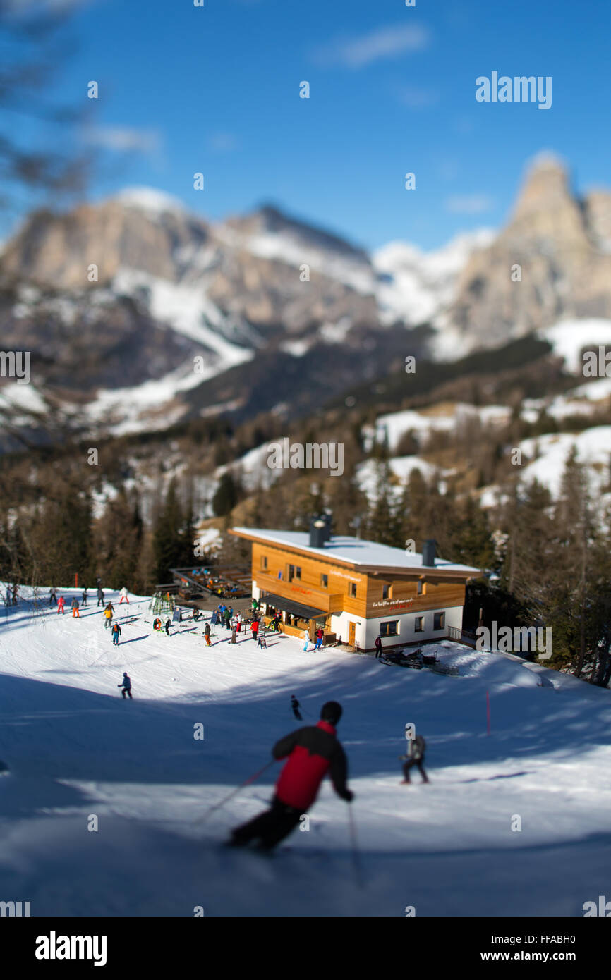 Tilt shift view of skiers and La Baita restaurant in the slopes of Alta Badia, Corvara, Dolomites, Belluno, Italy Stock Photo