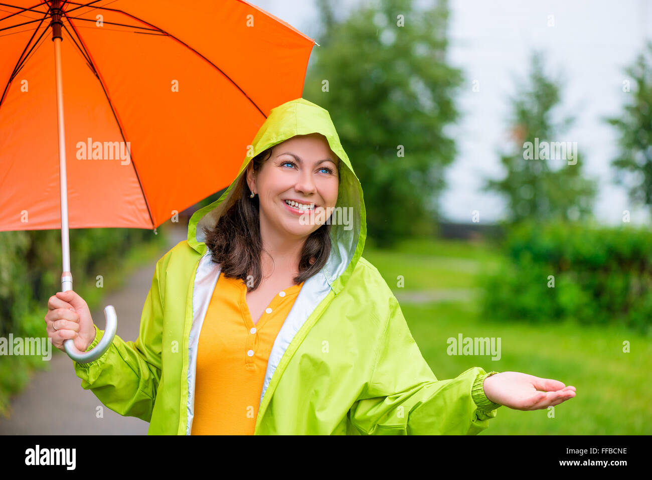 beautiful girl in a green raincoat and with an umbrella under the rain Stock Photo Alamy