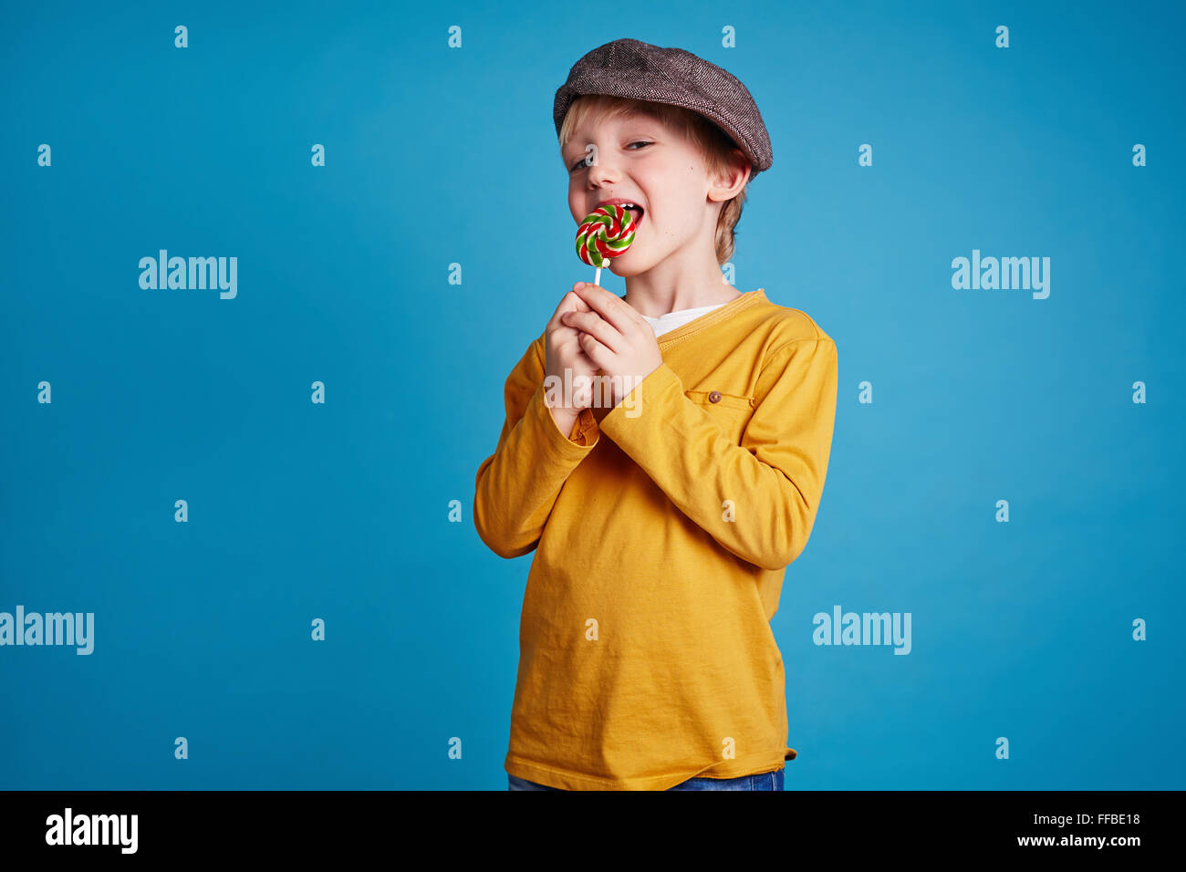 Happy boy in casualwear licking sugar candy Stock Photo