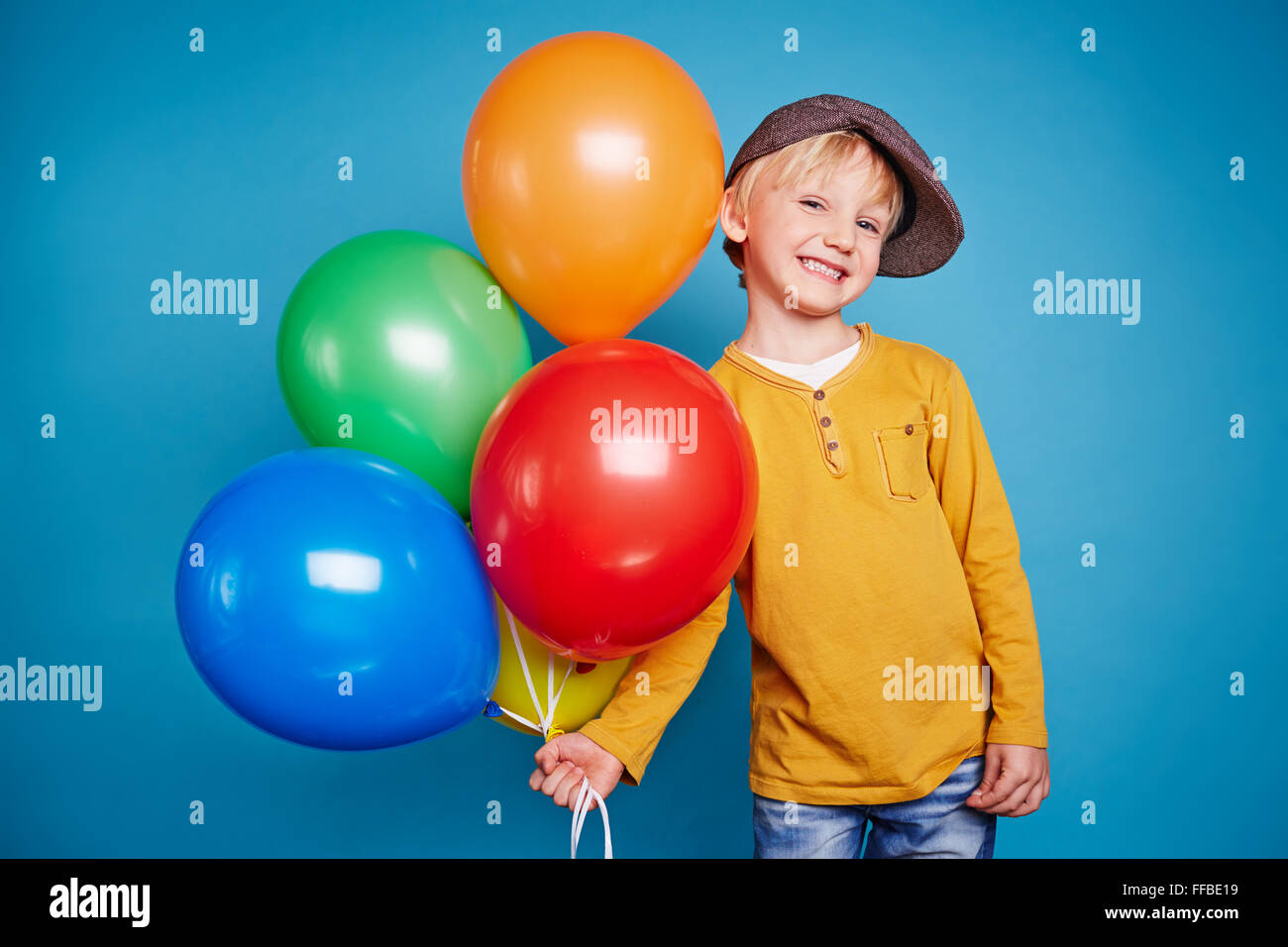Adorable youngster with several balloons looking at camera Stock Photo ...