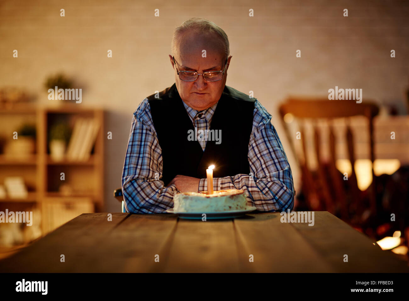 Mature man looking at birthday cake with one candle Stock Photo Alamy