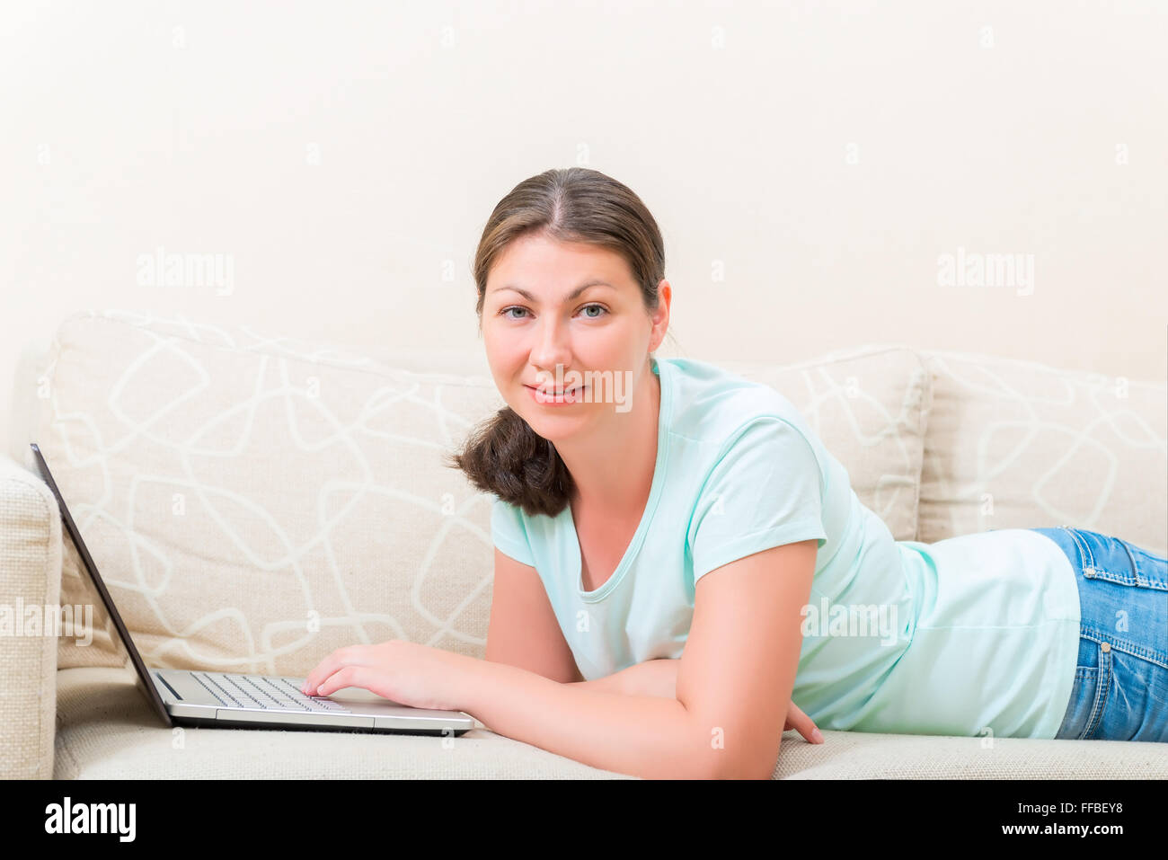 woman with laptop lying on the couch comfortably Stock Photo - Alamy