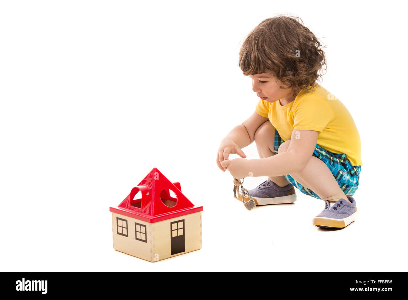 Happy toddler boy opening toy house isolated on white background Stock Photo