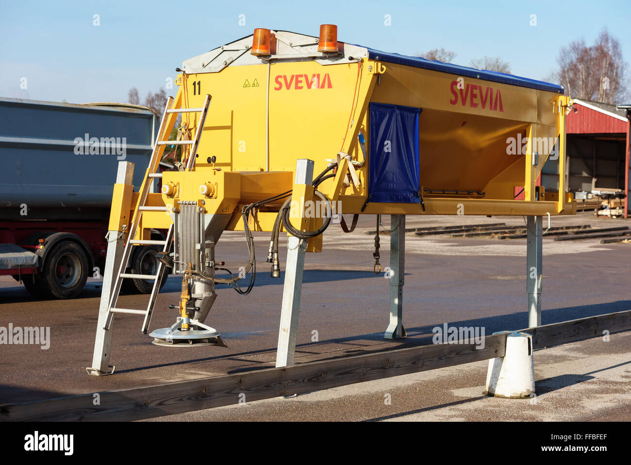 Brakne-Hoby, Sweden - February 07, 2016: A bright yellow Svevia road salt spreader stand on stilts on a parking lot outside a ha Stock Photo