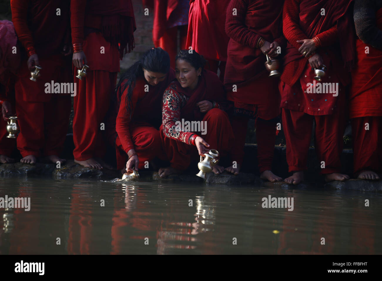 Kavre, Nepal. 12th Feb, 2016. Nepalese devotee women gather to collect holy water after offering prayers during the month-long Swasthani Bratakatha festival, devoted to goddess Shree Swasthani in Panauti, Kavre, Nepal on Friday, February 12, 16. Men devotees recite Holy Scripture and women pray for wellbeing of their spouses throughout the month-long fast via travelling barefooted to holy shrines for worship. Credit:  Skanda Gautam/ZUMA Wire/Alamy Live News Stock Photo