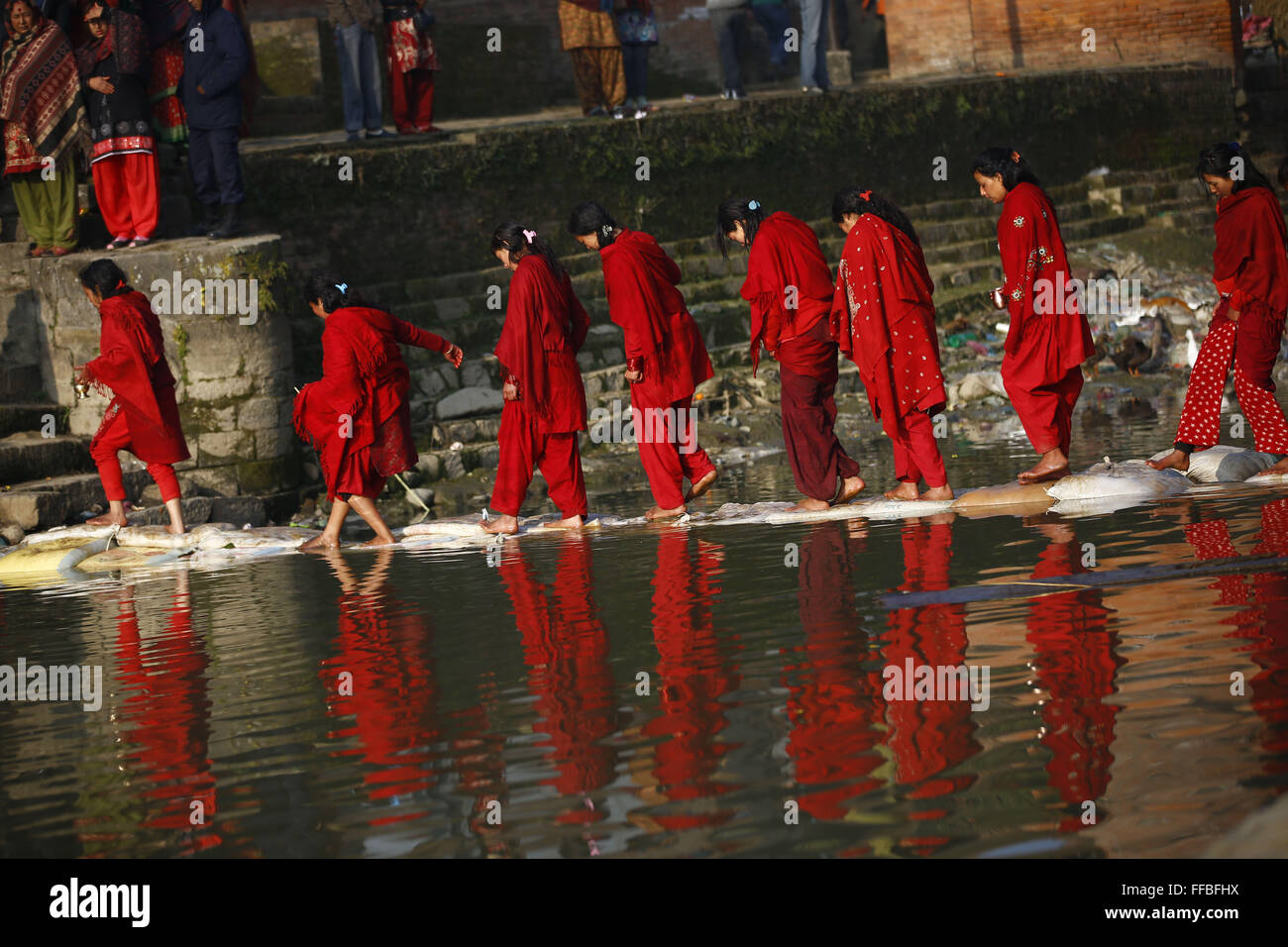 Kavre, Nepal. 12th Feb, 2016. Nepalese devotee women cross a temporary bridge after taking a holy bath during the month-long Swasthani Bratakatha festival, devoted to goddess Shree Swasthani in Panauti, Kavre, Nepal on Friday, February 12, 16. Men devotees recite Holy Scripture and women pray for wellbeing of their spouses throughout the month-long fast via travelling barefooted to holy shrines for worship. Credit:  Skanda Gautam/ZUMA Wire/Alamy Live News Stock Photo