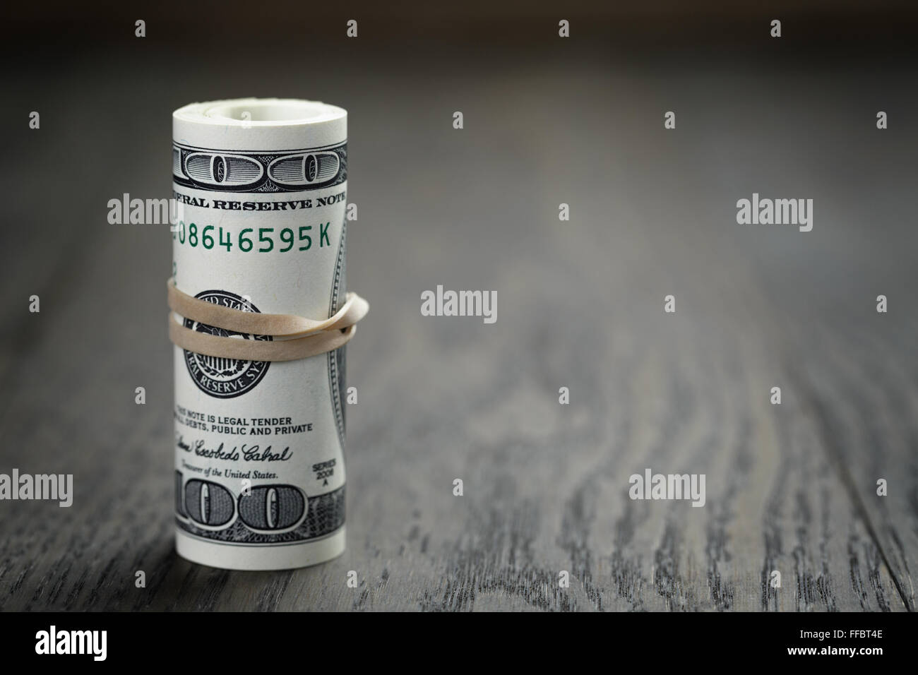 roll of new style hundred dollar bills on table Stock Photo