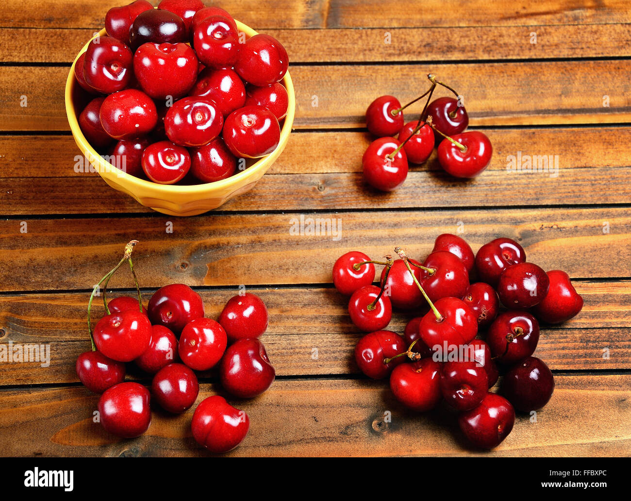 Yellow bowl with cherries on wooden table Stock Photo