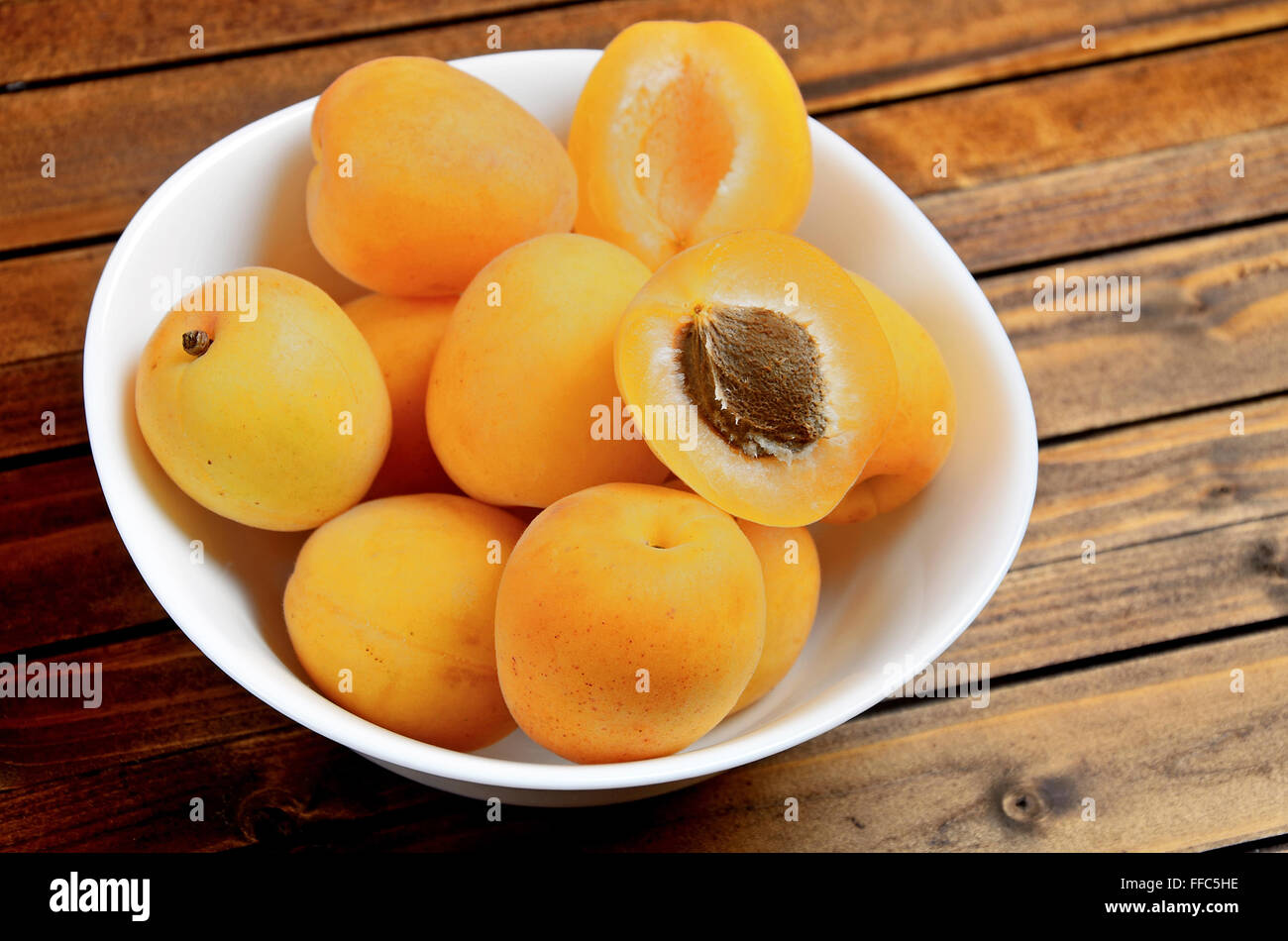 Bowl with apricots fruit on wooden table Stock Photo