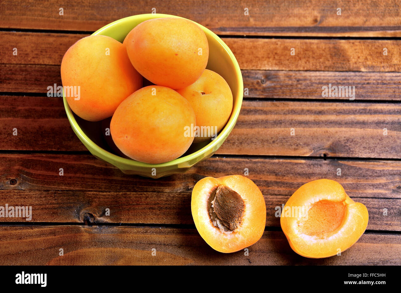 Green bowl with apricots fruit on table Stock Photo
