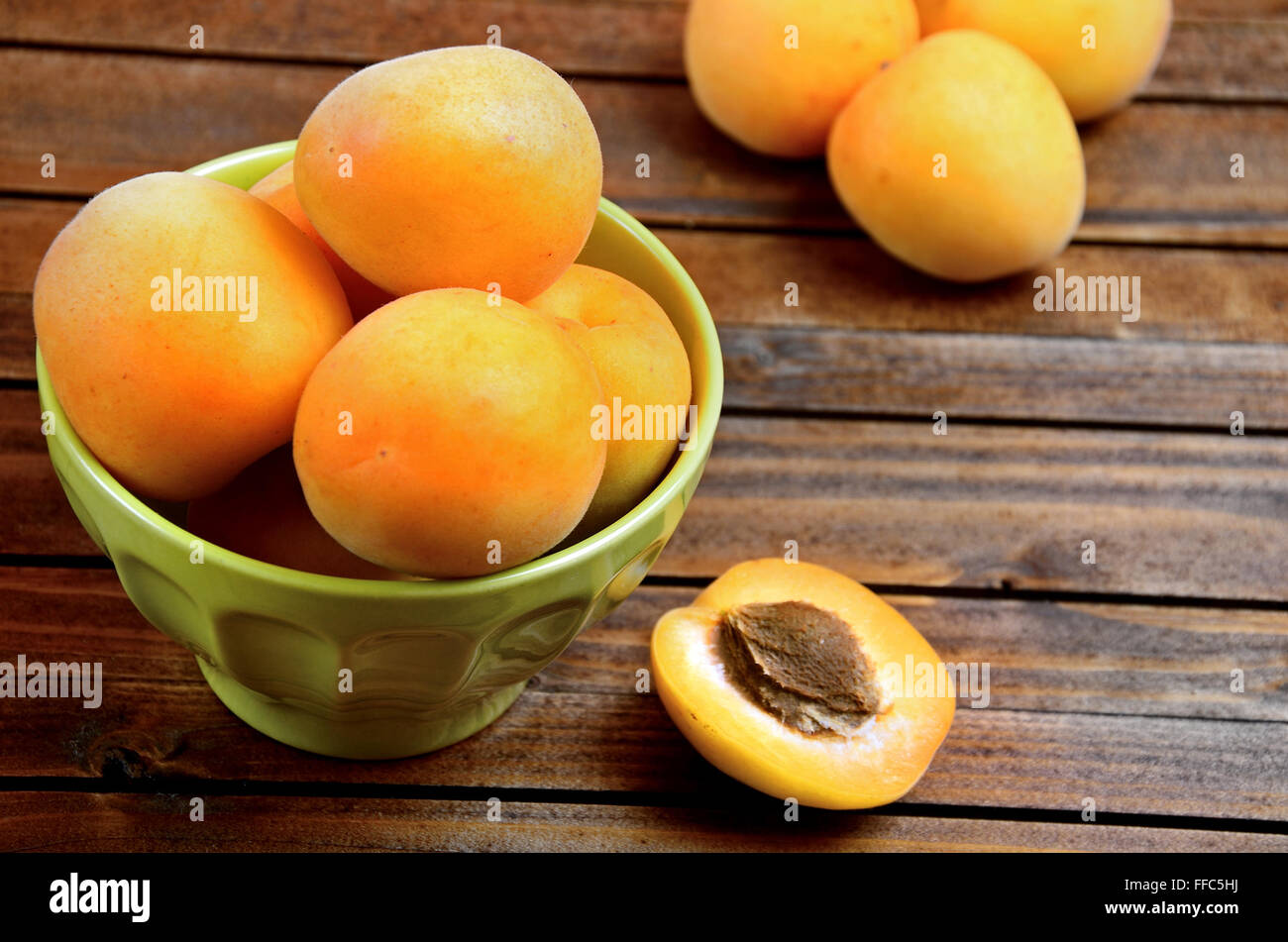 Green bowl with apricots on table Stock Photo
