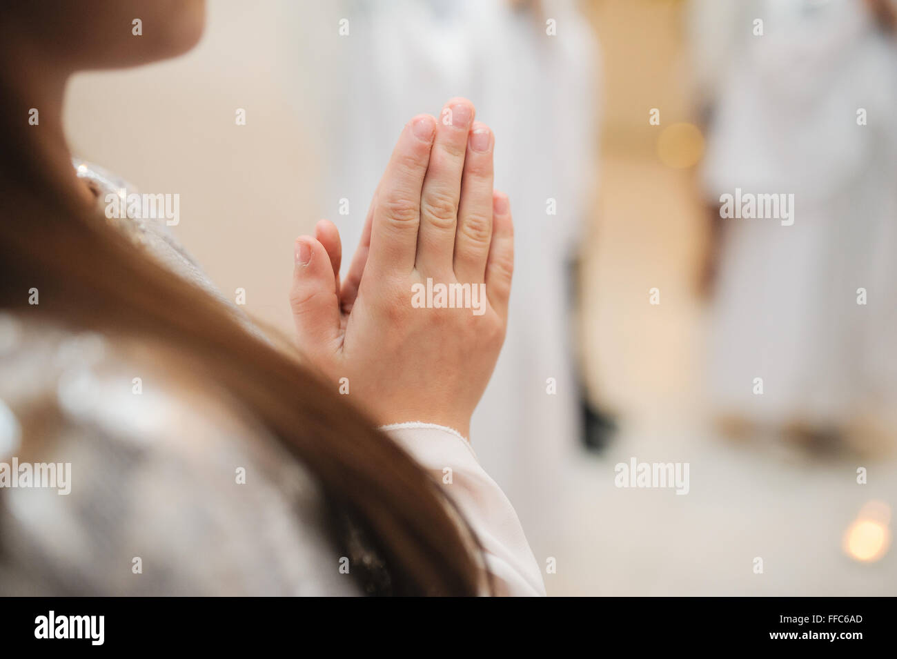 Little girl praying indoors. Focus on hands. Stock Photo